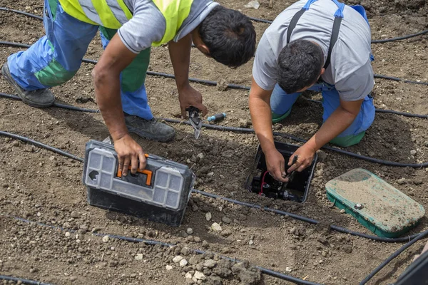 Garden workers installing irrigation control box — Stock Photo, Image