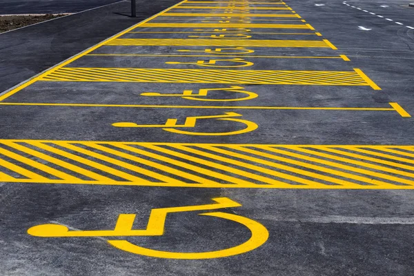 Parking lot with painted yellow sign of wheelchair — Stock Photo, Image