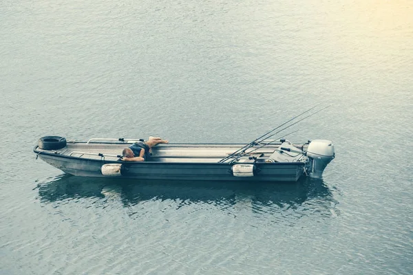 Homme couché dans le bateau et pêchant — Photo