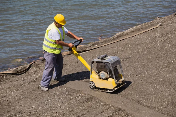 Builder worker at sand ground compaction — Stock Photo, Image