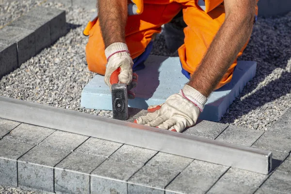 Construtor luvas mãos que colocam tijolos de pavimentação — Fotografia de Stock