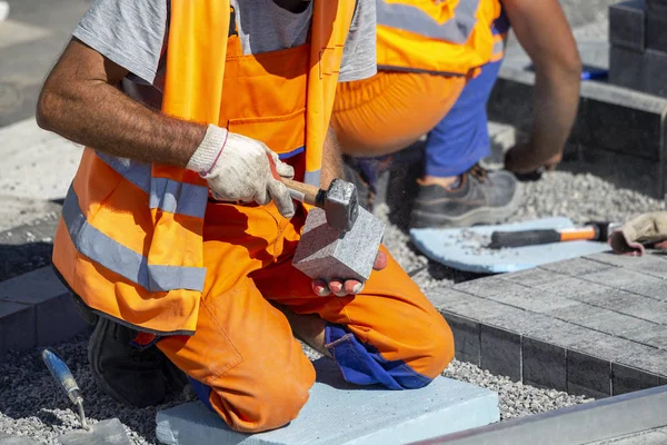 Trabalhador da construção em joelhos que põem tijolos de pavimentação ao ar livre — Fotografia de Stock