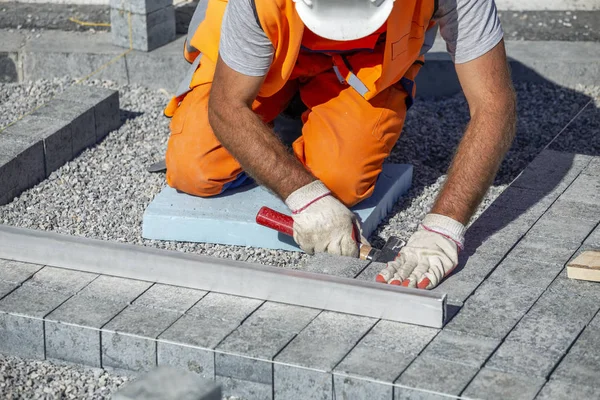 Trabajador de construcción de rodillas nivelación ladrillos de pavimentación — Foto de Stock