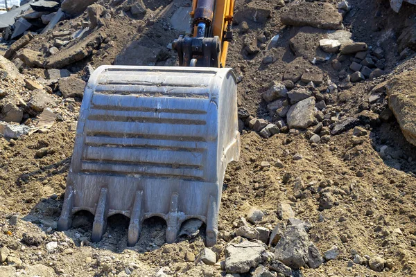 Cubo excavadora de hierro rompe el asfalto en el sitio de construcción — Foto de Stock