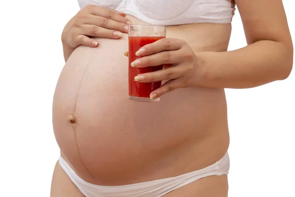 Mulher grávida segurando vidro frio de suco de tomate em sua barriga — Fotografia de Stock