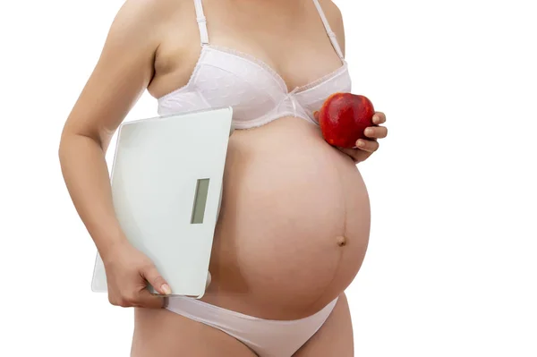 Kobieta w ciąży w bieliźnie z jabłkiem i wagą — Zdjęcie stockowe