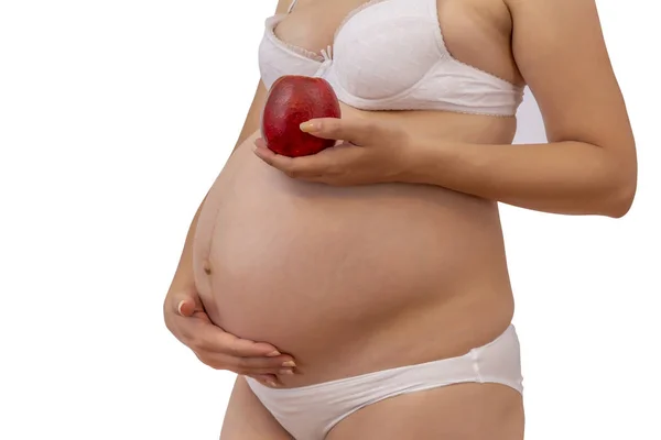 Mujer embarazada en ropa interior sosteniendo manzana roja sobre fondo blanco —  Fotos de Stock