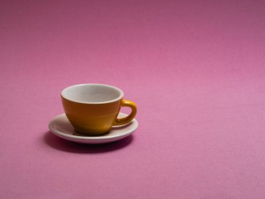 Sarı kahve fincanı ve içinde pembe arka planda doğum günü pastası.