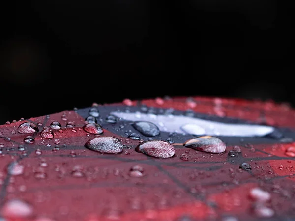 THREE ISOLATED DROPS OF RAIN ON A RED AND BLACK BACKGROUND