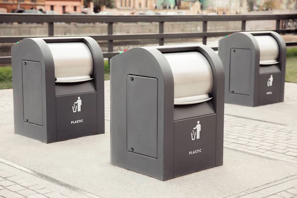 Ayrı çöp ve atık yığınları için üç siyah metal çöp kutusu..