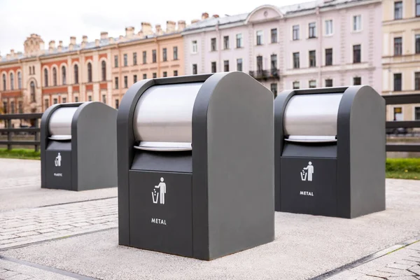 Ayrı çöp ve atık yığınları için üç siyah metal çöp kutusu..