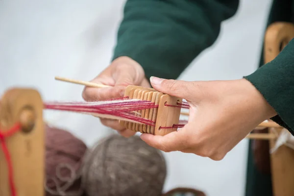 Kadınların elleri doğal iplik ürünlerinin renkli ipliklerini dokuyor. Güzel bir arka plan, nakış ve doğal malzemeler kavramı..