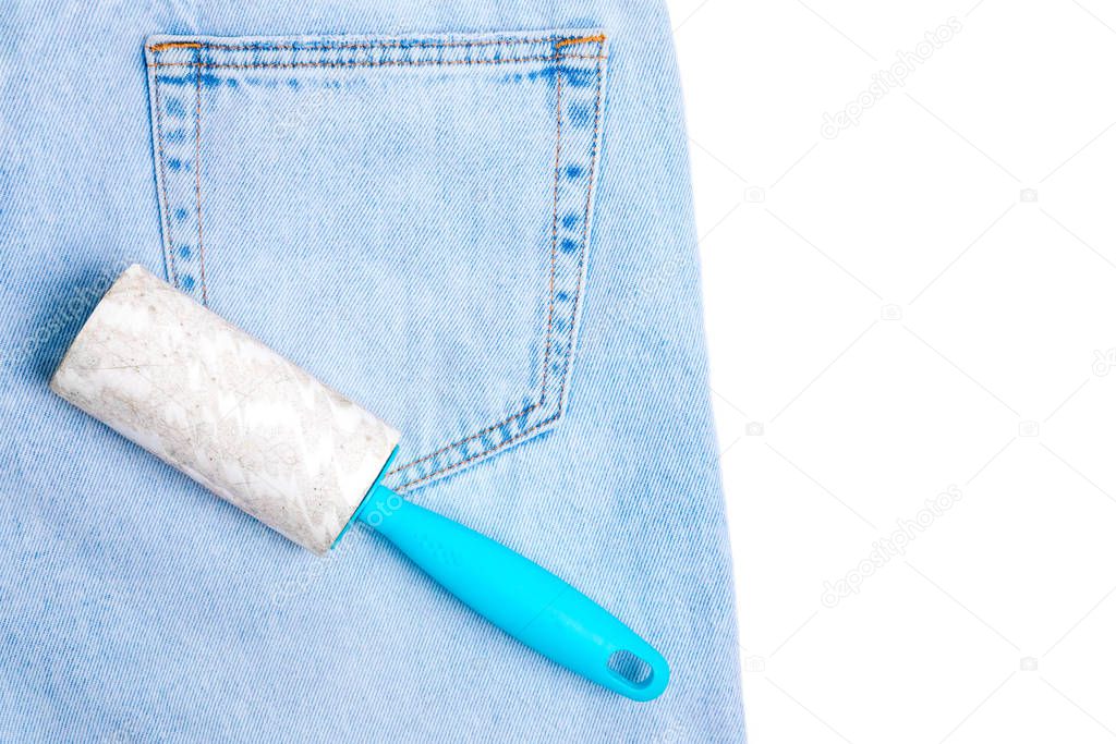 Dirty reusable clothes cleaning roller on blue jeans background.