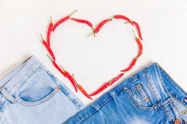 İki çift kot pantolon ve beyaz desenli arka planda kırmızı biberli bir kalp..