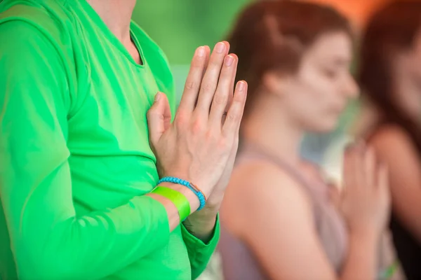 Genç beyaz bir adam grup halinde yoga yaparken el ele tutuşmuş..