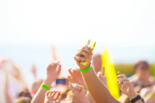 Soyut bir arka plan. Bir adam bir müzik festivalinde insanların ellerini gökyüzüne karşı bulanık bir şekilde telefonuyla tatil fotoğrafı çekiyor..