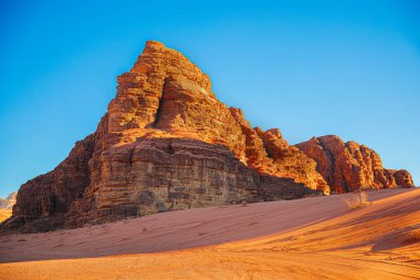 Mavi gökyüzüne karşı kırmızı ve turuncu kumdan desenli kum dağı, Ürdün, Wadi Rum Çölü.