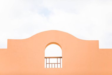 Mavi gökyüzünde, kemer şeklinde turuncu bir binanın duvarının bir parçası. Seyahat için yumuşak bir arka plan, otel konaklama, popüler renkler görünümü.