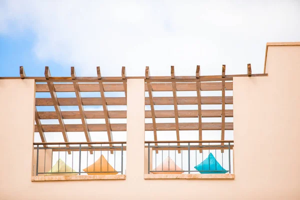 Pembe bir binanın duvarının bir kısmı ve mavi gökyüzünün ahşap çatısı altında dinlenmek için çok renkli yastıklar. Seyahat için yumuşak bir arka plan, otel konaklama, popüler renkler görünümü.