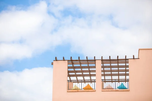 Pembe bir binanın duvarının bir kısmı ve mavi gökyüzünün ahşap çatısı altında dinlenmek için çok renkli yastıklar. Seyahat için yumuşak bir arka plan, otel konaklama, popüler renk manzarası. Boşluğu kopyala.