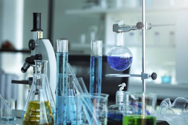 Kimya biyolojisi test örnekleri için farklı cam ekipmanlar. Sıvı, yansıyan metal mikroskop, test tüpleri. Mavi ton, Araştırma, Geliştirme ve Sağlık Hizmetleri kavramı.