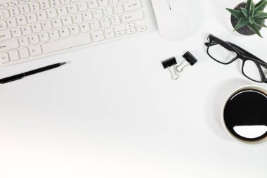 Beyaz ofis masasında yatıyordu. Yukarıdan klavye, bilgisayar faresi, kalem, belge klipsleri, gözlük ve bir fincan sade kahve ile görüntüle. Kopyalama alanı olan üst görünüm.