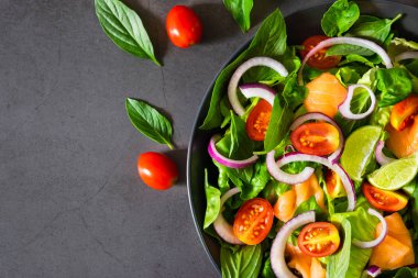 Somon salatası, yukarıdan manzara, taze domates, soğan, ıspanak, marul ve fesleğen. Sağlıklı yemek, ev yapımı konsept. Diyet, lezzetli ve sağlıklı yemek için sebze. Üst görünüm, alanı kopyala.