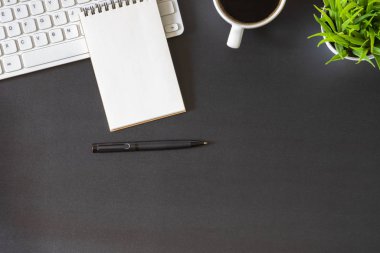 Ofiste beyaz masalı bir iş yeri. Not defteri ve fincan kahveyle klavyenin üstünden en iyi görüntü. Modern yaratıcı tasarımcılar için yer var. Fotokopi alanı olan düz bir yer. İş ve finans kavramı.