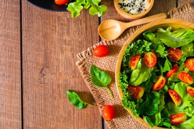 Kırmızı kiraz domatesli taze yeşil sebze, soğan ve marullu ıspanak. Tahta kasede salata susamı sosu. Lezzetli ve sağlıklı yemekler için diyet menüsü. Düz, kopyalama alanı ile.