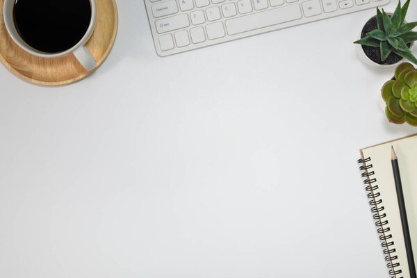 Workspace office with a white desk. Top view from above with keyboard, notebook and pencil with a white cup coffee on the wooden plate. Flat lay with copy space. Business and finance concept.