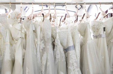 Arka planda güzel, beyaz gelinlik dokusu. Düğün elbiseleri, gelinlik salonunun iç tarafındaki askıda asılı. Tasarım, moda modern lüks detaylarıyla.