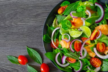 Somon salatası, taze domates, soğan, ıspanak, marul, siyah arka planda fesleğen. Sağlıklı yemek, ev yapımı konsept. Lezzetli ve lezzetli. Düz yat, boşluğu kopyala.