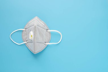 Mavi arka planda tıbbi maske var. Kirlilik ve gribe karşı korunma yüzü. Koronavirüsten (COVID-19) ya da 2019-nCoV 'dan yayılmaması için önleme hijyeni. Sağlık ve Tıp Konsepti.