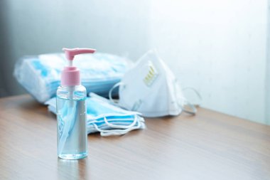 Tahta masadaki tıbbi maskeli el dezenfektanı jeli yakın çekim. Korunma, hastalık koronavirüsü (2019-nCoV) el hijyeni ve solunum sistemi. Ellerini sık sık yıkayarak ve maske takarak..