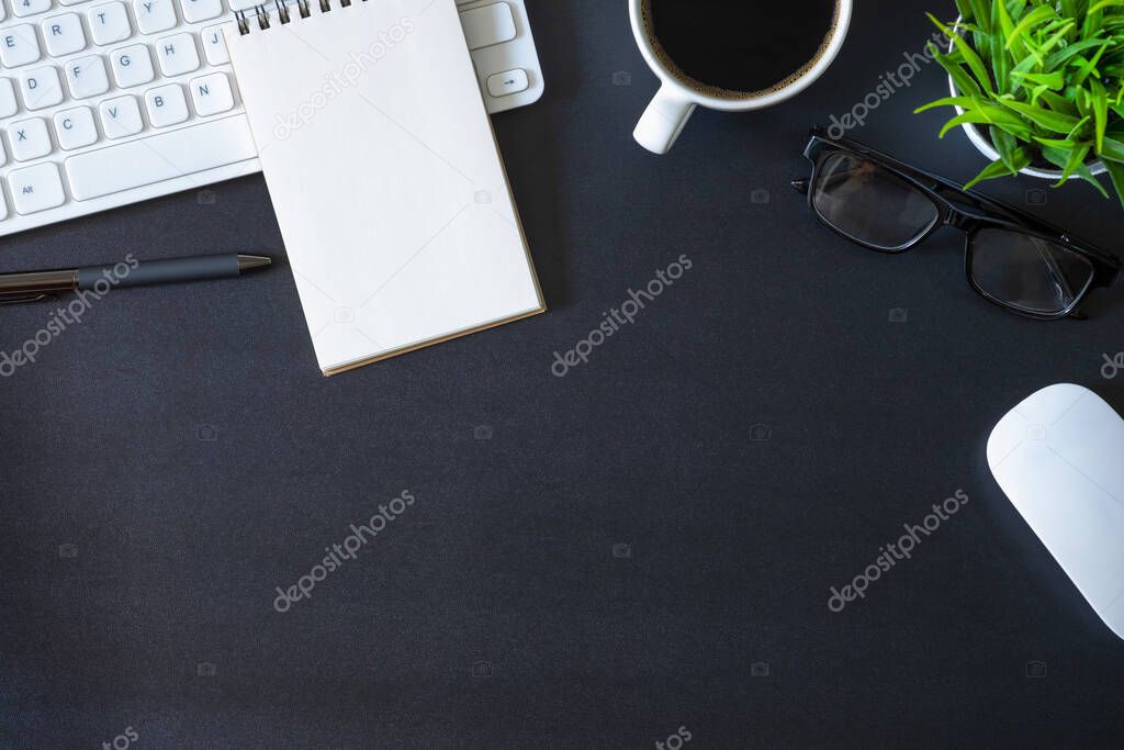 Workplace office with dark black desk. Top view from above of keyboard with notepad and coffee cup. Space for modern creative work of designer. Flat lay with copy space. Business and  finance concept.