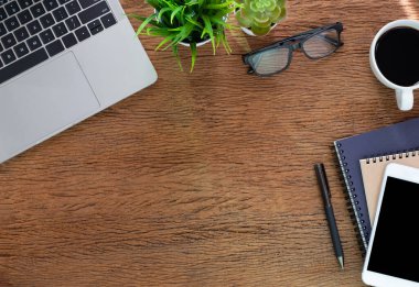 Evde ahşap masalı bir iş yeri. Dizüstü bilgisayarın üstünde kahve ve defter var. Modern yaratıcı tasarımcılar için ofis alanı. Boş fotokopi alanı olan düz bir yer. İş finans kavramı.