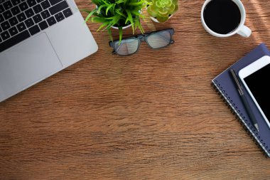 Evde ahşap masalı bir iş yeri. Dizüstü bilgisayarın üstünde kahve ve defter var. Modern yaratıcı tasarımcılar için ofis alanı. Boş fotokopi alanı olan düz bir yer. İş finans kavramı.