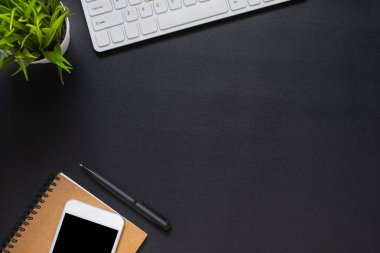 Ofiste, çalışma masası siyah. Not defteri ve telefonuyla klavyenin üstünden en üstteki görünüm. Modern yaratıcı tasarımcılar için yer var. Boş fotokopi alanı olan düz bir yer. İş ve finans kavramı.