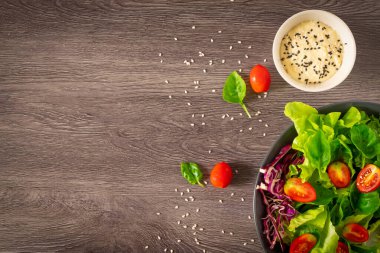 Taze yeşil sebze yaprakları karışımı. Sağlıklı yemek salatası, ıspanak, marul, siyah kasede kırmızı lahana, salata susamı sosu. Ev yapımı, lezzetli sebzeler ve fotokopi alanı olan yemekler.