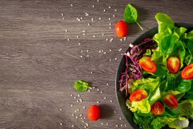 Taze yeşil sebze yaprakları karışımı. Sağlıklı yemek salatası, ıspanak, marul, siyah kasede kırmızı lahana, salata susamı sosu. Ev yapımı, lezzetli sebzeler ve fotokopi alanı olan yemekler.