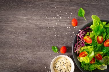 Taze yeşil sebze yaprakları karışımı. Sağlıklı yemek salatası, ıspanak, marul, siyah kasede kırmızı lahana, salata susamı sosu. Ev yapımı, lezzetli sebzeler ve fotokopi alanı olan yemekler.