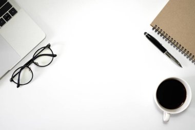 Ofiste beyaz masalı bir iş yeri. Not defteri ve kahveyle dizüstü bilgisayarın üst görüntüsü. Modern yaratıcı tasarımcılar için yer var. Boş fotokopi alanı olan düz bir yer. İş ve finans kavramı.