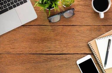 Evde ahşap masalı bir iş yeri. Dizüstü bilgisayarın üstünde kahve ve defter var. Modern yaratıcı tasarımcılar için ofis alanı. Boş fotokopi alanı olan düz bir yer. İş finans kavramı.