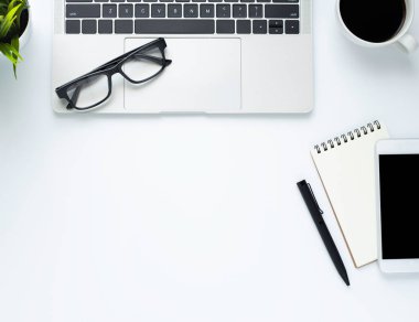 Ofiste beyaz masalı bir iş yeri. Dizüstü bilgisayarın üstünde kahve ve defter var. Modern yaratıcı tasarımcılar için yer var. Boş fotokopi alanı olan düz bir yer. İş ve finans kavramı.