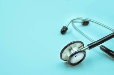 Açık mavi arka plan kontrolü için Black Stetoscope 'a yakın çekim. Stetoskop ekipmanları ses tanısı koymak için kullanılır. Fotokopi alanına sahip sağlık ve kardiyoloji kavramı.