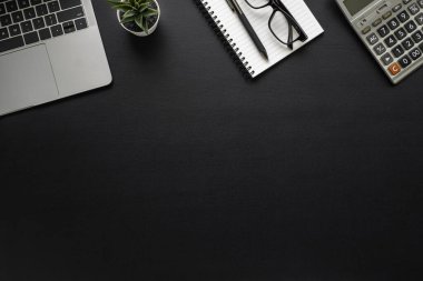 Ofiste, çalışma masası siyah. Not defteri ve gözlüklerle dizüstü bilgisayarın üst görüntüsü. Modern yaratıcı tasarımcılar için yer var. Boş fotokopi alanı olan düz bir yer. İş ve finans kavramı.