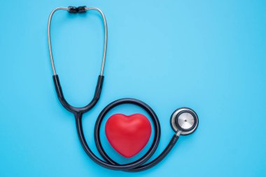 Siyah steteskop, mavi arka planda kontrol için doktorun kırmızı kalbi. Stetoskop ekipmanları ses tanısı koymak için kullanılır. Sağlık ve kardiyoloji konsepti. Kopyalama alanı olan düz.