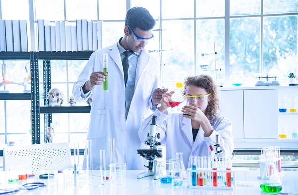 Молода жінка і чоловік оглядають, вчені, техніки або студенти, які проводять дослідження або експеримент, використовуючи наукове, медичне обладнання або пристрій в хімічній лабораторії — стокове фото