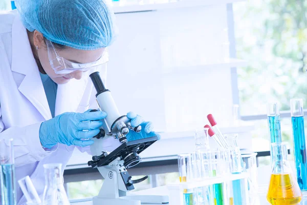 Asian woman scientist, researcher, technician, or student conducted research or experiment by using microscope which is scientific equipment in medical, chemistry or  biology laboratory — Stock Photo, Image