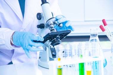 Asya kadın bilim adamı, araştırmacı, teknisyen veya öğrenci tıbbi, Kimya veya biyoloji laboratuarında Bilimsel ekipman olan mikroskop kullanarak araştırma veya deney yaptı